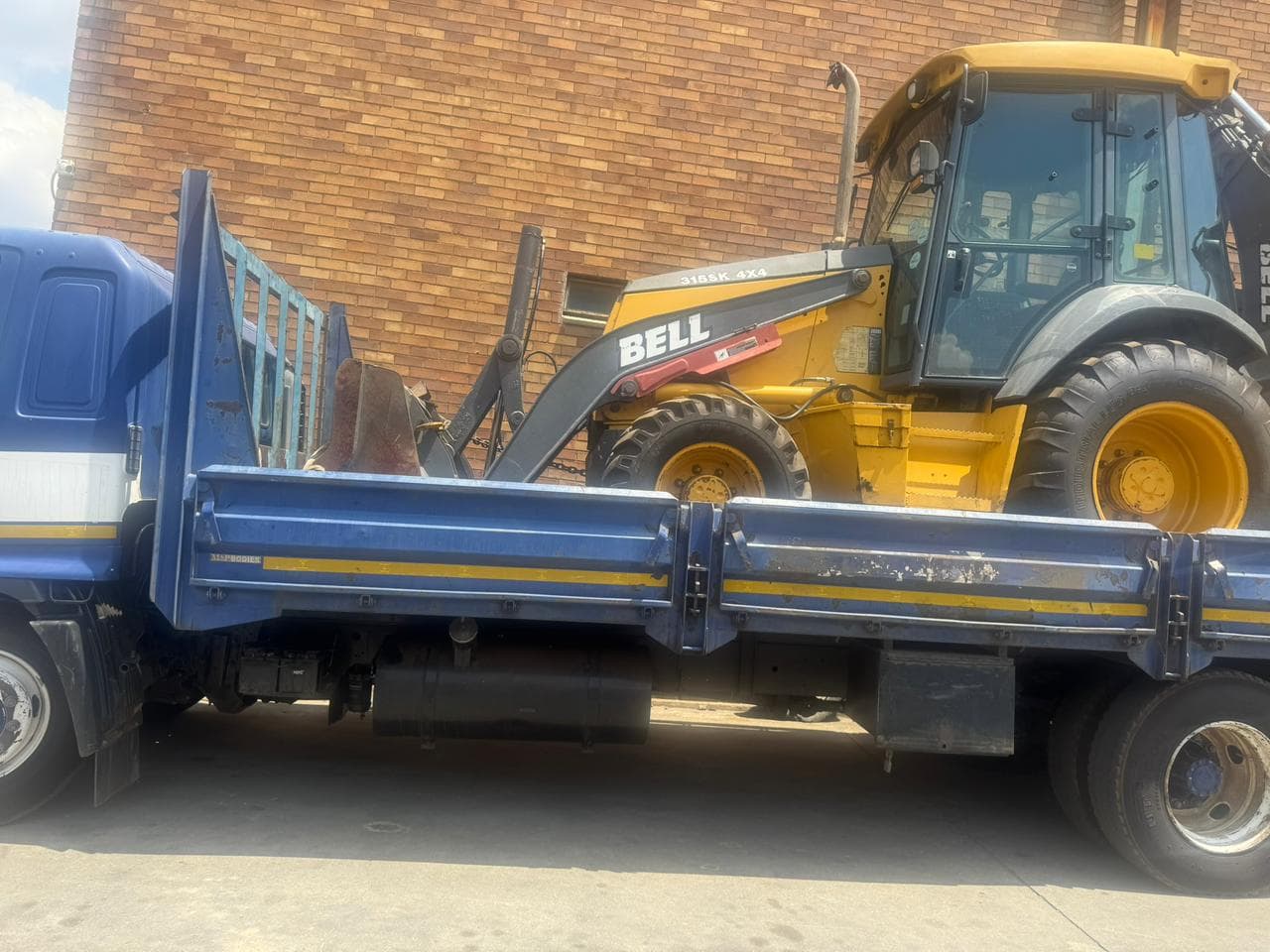 Drop-side truck loaded with a Bell backhoe